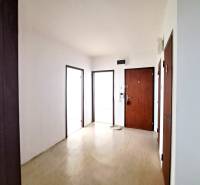 Négyszobás lakás előszobája fa mintázatú padlóval és fa ajtókkal.