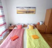 Hálószoba üdülőapartmanban két ággyal, festménnyel és színes ágyneművel.