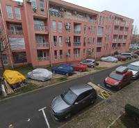 Nyaraló apartman Burgaszban, rózsaszín épület előtt parkoló autókkal.