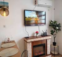 Nyaraló apartman belső tere kandallóval, televízióval és étkezőasztallal.