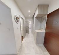 Folyosó egy kétszobás lakásban fogasfallal és fehér falakkal.