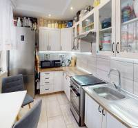 Konyha egy kétszobás lakásban fehér szekrényekkel és ezüst készülékekkel.