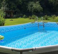 Felfújható medence a nyaraló kertjében, zölddel körülvéve a Tisovec-i Hviezdoslav utcában.