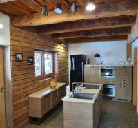 Rusztikus konyha egy faházban fa dekorációkkal, világos bútorokkal és mennyezeti gerendákkal.