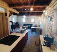 Faház fa elemekkel és cserépkályhával, fa dekorációjú padlóval, konyhaszigettel.