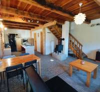 Egy fahatású padlóval, fából készült mennyezettel és cserépkályhával rendelkező házikó belső tere.