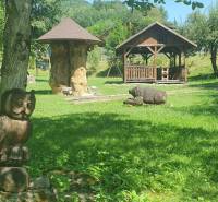 Kert a Hviezdoslav utca Tisovecben faház melletti fa szobrokkal.