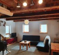 Egy kunyhó belseje cserépkályhával, kanapéval és tömör gerendákból készült fa mennyezettel.