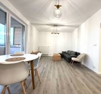 Nappali egy háromszobás lakásban kanapéval, asztallal és fa dekorációjú padlóval.