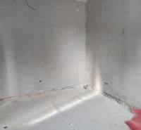 Üres belső tér vakolatlan falakkal és betonpadlóval egy családi házban.