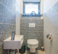 Fürdőszoba családi házban mosdóval, WC-vel és hangulatos burkolattal.