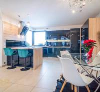 Világos konyha étkezőasztallal és bárszékekkel egy családi házban.