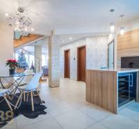 Családi ház belső tere étkezőasztallal, lépcsővel és karácsonyfával.