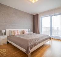 Hálószoba családi házban ággyal, éjjeliszekrényekkel és fa dekoros padlóval.