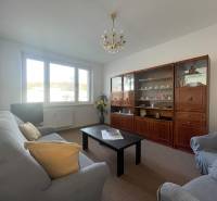 Obývací szoba egy háromszobás lakásban kanapéval, fotelekkel és nappali szekrénnyel.