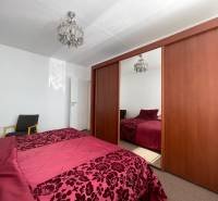 Hálószoba nagy szekrénnyel, csillárral és ággyal egy háromszobás lakásban.