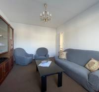 Nappali egy háromszobás lakásban kényelmes kanapéval, fotelekkel és vitrinnel.