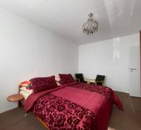 Hálószoba mintás ágyneművel, mennyezeti lámpával és gardróbszekrénnyel egy háromszobás lakásban.