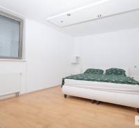 Hálószoba egy háromszobás lakásban fa mintázatú padlóval és nagy ággyal.