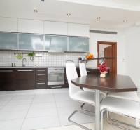 Fehér csempés és sötét bútorokkal berendezett konyha egy háromszobás lakásban, modern felszereléssel kiegészítve.