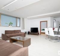 Világos nappali egy háromszobás lakásban kanapéval és étkezőasztallal.