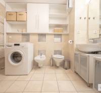 Fürdőszoba egy háromszobás lakásban mosógéppel, WC-vel és bidével, csempével és szekrényekkel.