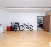 3 szobás lakás belső tere fa dekoros padlóval, íróasztallal és kerékpárral.