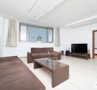 Nappali sötét kanapékkal, dohányzóasztal, televízió és fa dekorációjú padló.