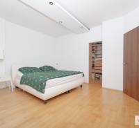 Hálószoba egy háromszobás lakásban, ággyal, fa dekoros padlóval és beépített szekrénnyel.