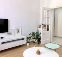 Nappali egy kétszobás lakásban, TV-vel, asztallal és fa dekor padlóval.