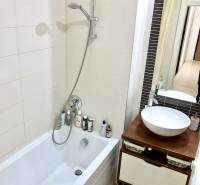 Fürdőszoba egy kétszobás lakásban káddal, zuhanyzóval és stílusos mosdószekrénnyel.