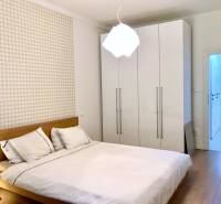 Hálószoba egy kétszobás lakásban fehér szekrénnyel és fa mintázatú padlóval.