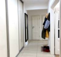 Folyosó csempével és szekrénnyel egy kétszobás lakásban, ruhafogasokkal.