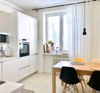 Konyha egy kétszobás lakásban fehér szekrényekkel és étkezőasztallal székekkel.