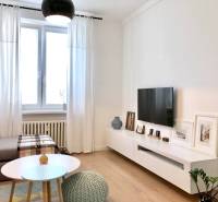 Nappali egy kétszobás lakásban, televízióval, kanapéval és fa dekorációjú padlóval.