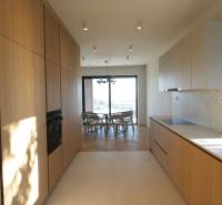 Konyha egy 4 szobás lakásban, fa dekoros padlóval és világos konyhabútorral.