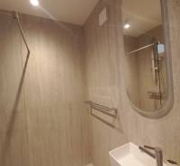 Fürdőszoba zuhanyzóval és mosdóval egy négy szobás lakásban.