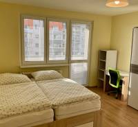 Hálószoba franciaággyal, íróasztallal és fa dekorációjú padlóval egy háromszobás lakásban.