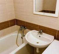 Fürdőszoba káddal, mosdóval és mosógéppel egy háromszobás lakásban, világos csempékkel.