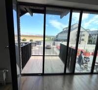 Kilátás egy kétszobás lakásból az erkélyre, fa dekor padlóval.