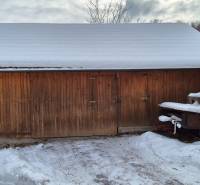 Az Ochodnicéből származó fényképen egy családi ház melletti, hóval borított fa tárolóépület látható.