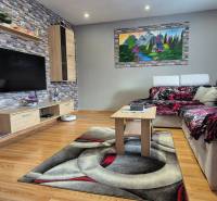 Nappali egy családi házban, fa dekoros padlóval, kővel a falon és kényelmes kanapéval.