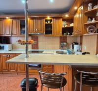 Konyha egy családi házban fa szekrényekkel, bárpulttal és háztartási gépekkel.