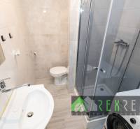 Fürdőszoba egy háromszobás lakásban mosdóval, zuhanyzóval és mosógéppel.