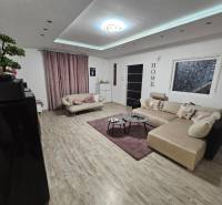 Nappali egy családi házban, fa dekorációjú padlóval és nagy kanapéval.