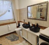 Fürdőszoba családi házban dupla mosdóval, káddal és mosógéppel a csempén.