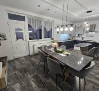 Étkező tér kőasztallal, szürke székekkel és függő lámpákkal egy családi házban.