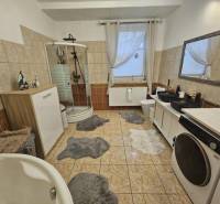 Fürdőszoba családi házban káddal, zuhanyzóval és mosógéppel.