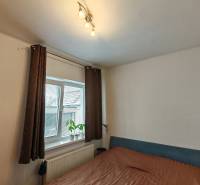 Hálószoba családi házban, ággyal, polcokkal és ablakkal, dekoratív növénnyel.