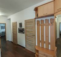 Családi ház folyosója fa dekorációs padlóval, fogasokkal és könyvespolccal.